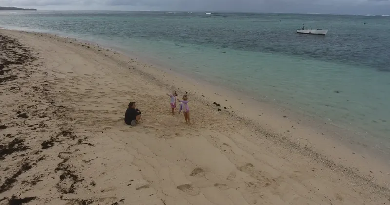 Two Duckies and a parent on the empty Le Morne beach, seen from the drone.