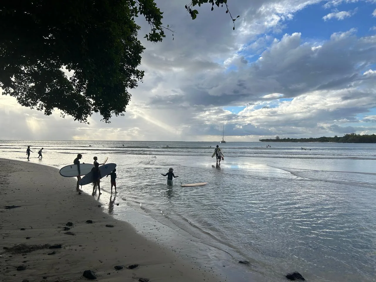 Duckies carrying their boards into Tamarin Bay at dusk.